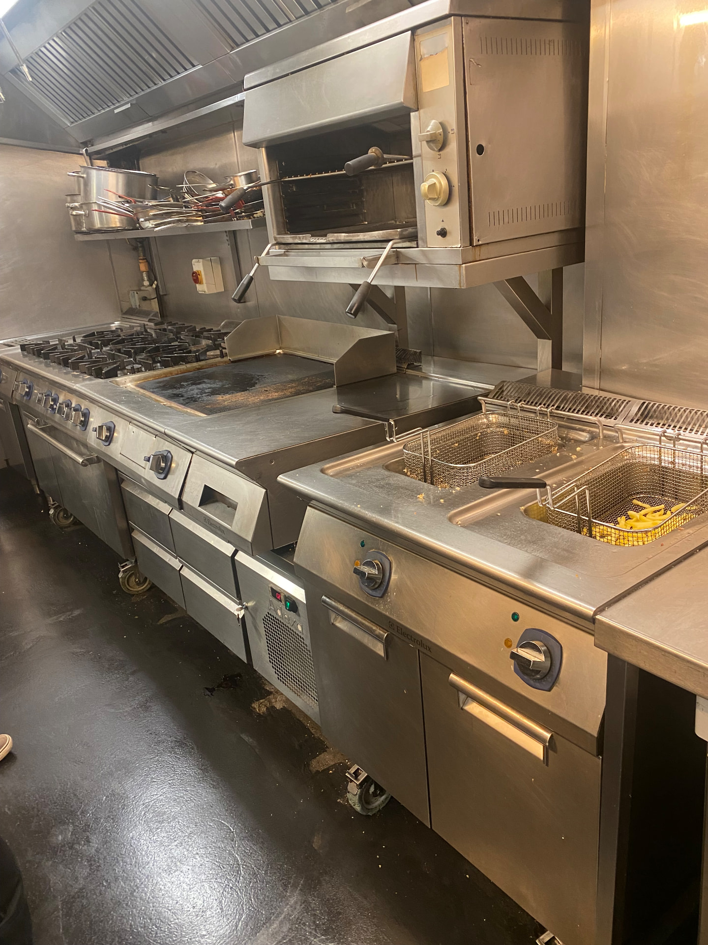 Commercial gas range, griddle, fryer and salamander grill serviced under a canopy in a London restaurant kitchen