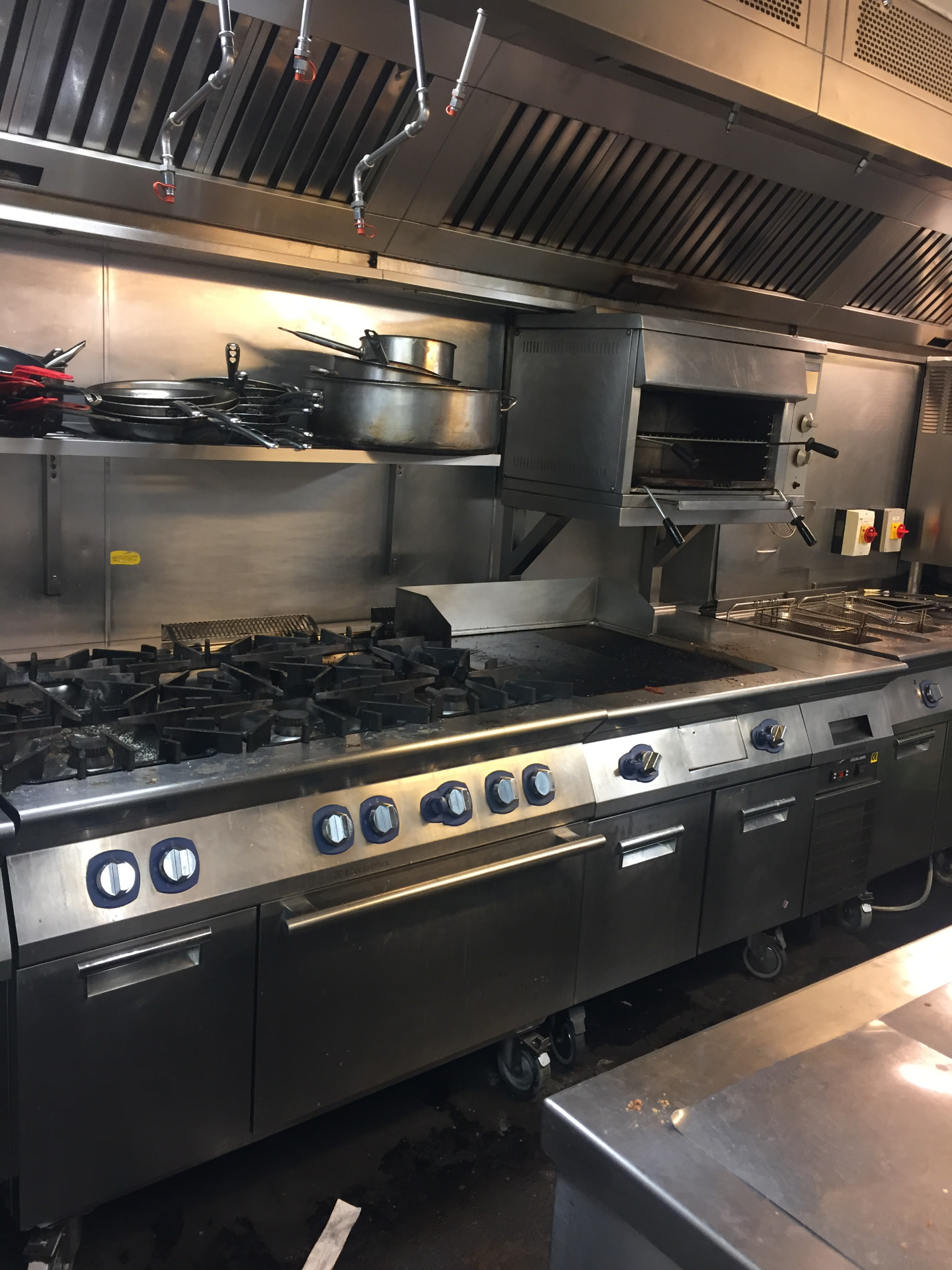 Commercial kitchen extraction canopy above a gas range line with interlock and fire suppression in a London kitchen